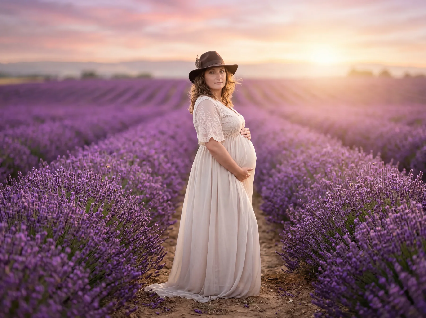 An expectant mother standing among lavender beneath a pastel sky