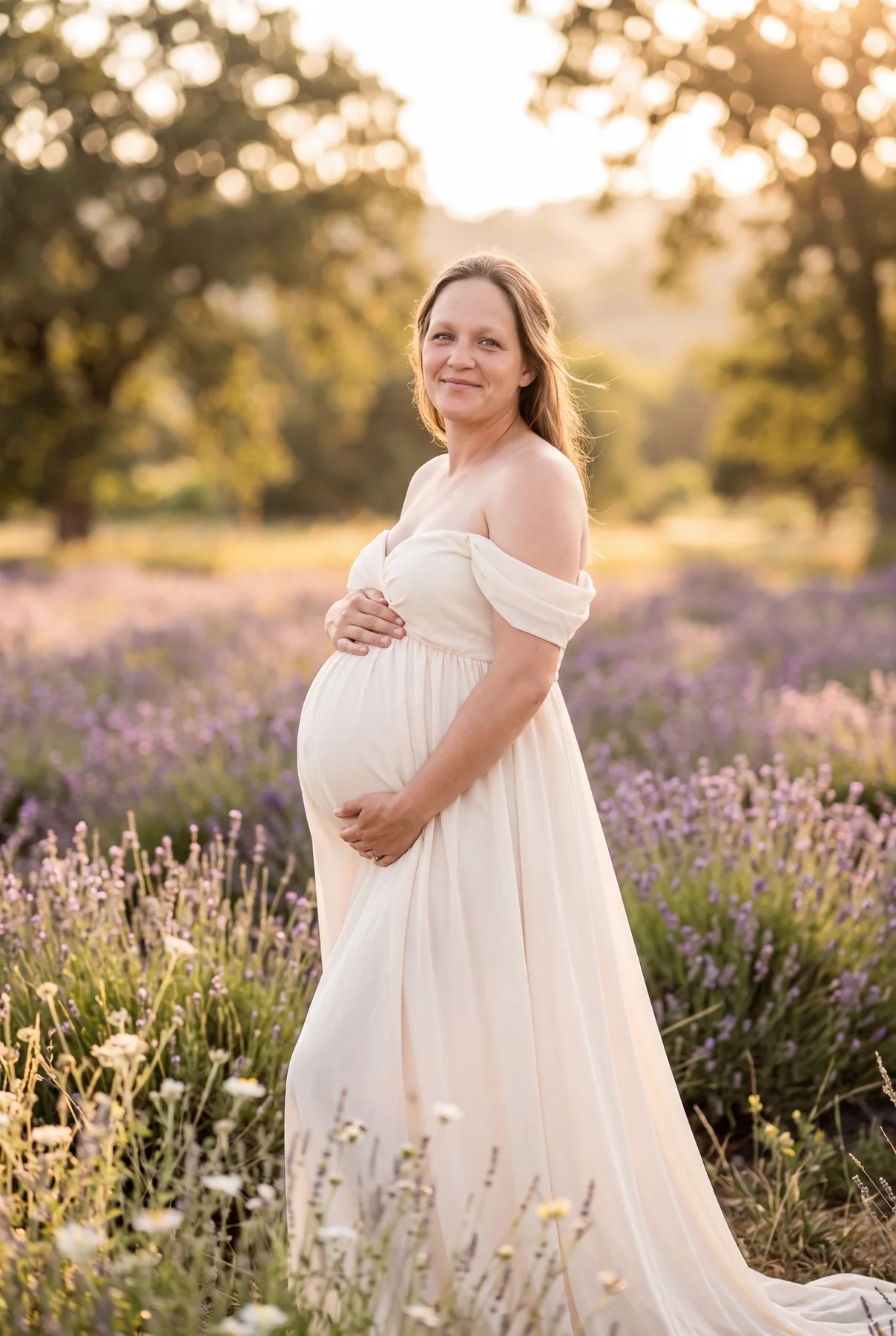 An expectant mother in a white dress standing in a lavender field