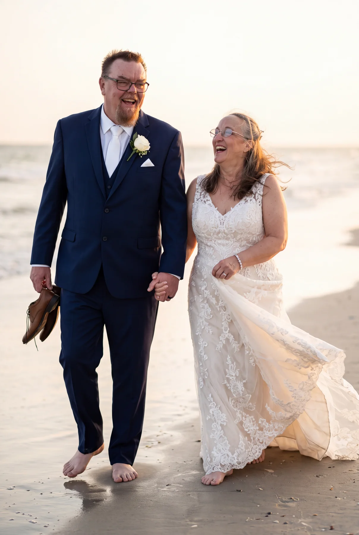A close view of a bride and groom walking together beside the sea